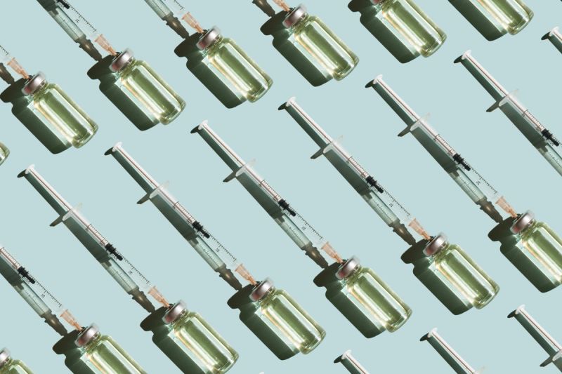 Pattern of vials and syringes with a vaccine on a blue background. Concept of medical treatment or vaccination.
