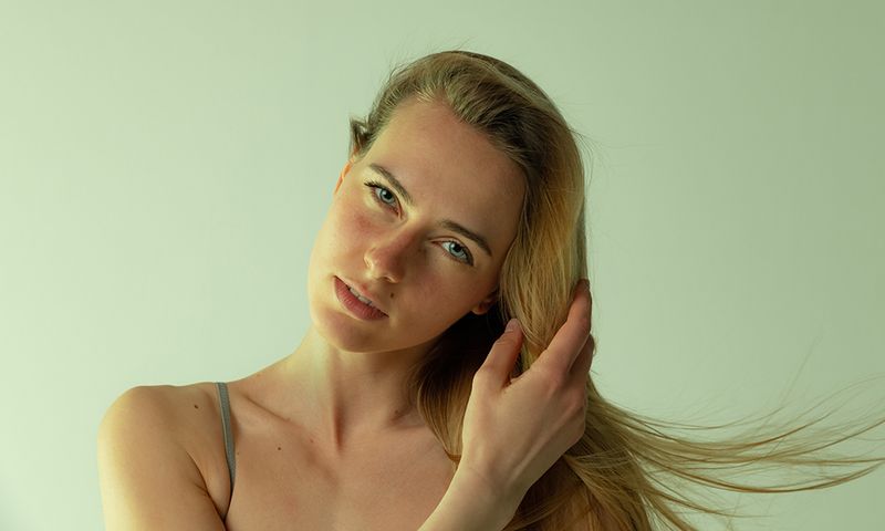 Portrait of tender young woman posing, looking at camera isolated over grey studio background. Tenderness. Concept of beauty, body and skin care, health, plastic surgery, cosmetics, ad