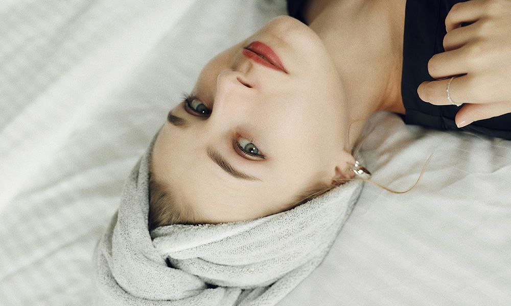 woman lying on bed with towel on hair