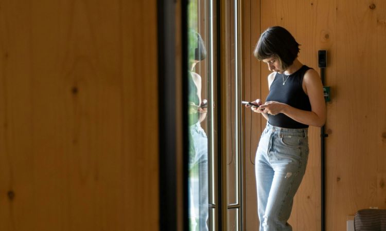woman looking at phone in front of glass window