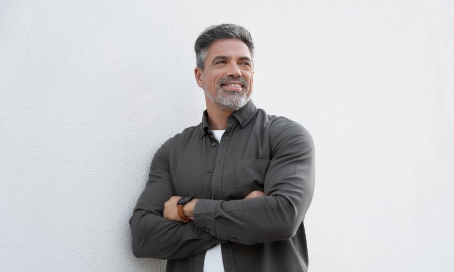 Smiling mature man standing crossed arms isolated on white background