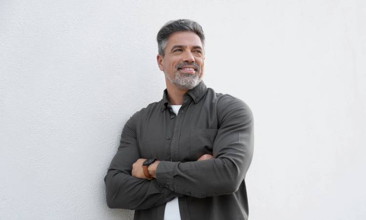 Smiling mature man standing crossed arms isolated on white background