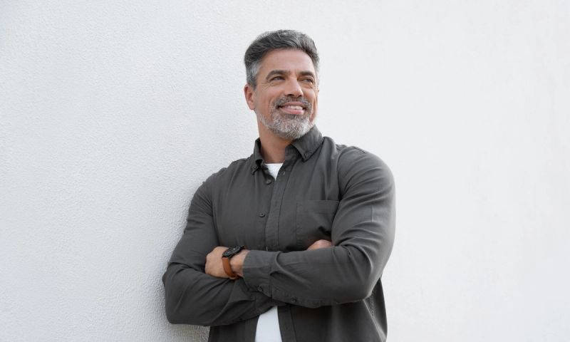 Smiling mature man standing crossed arms isolated on white background