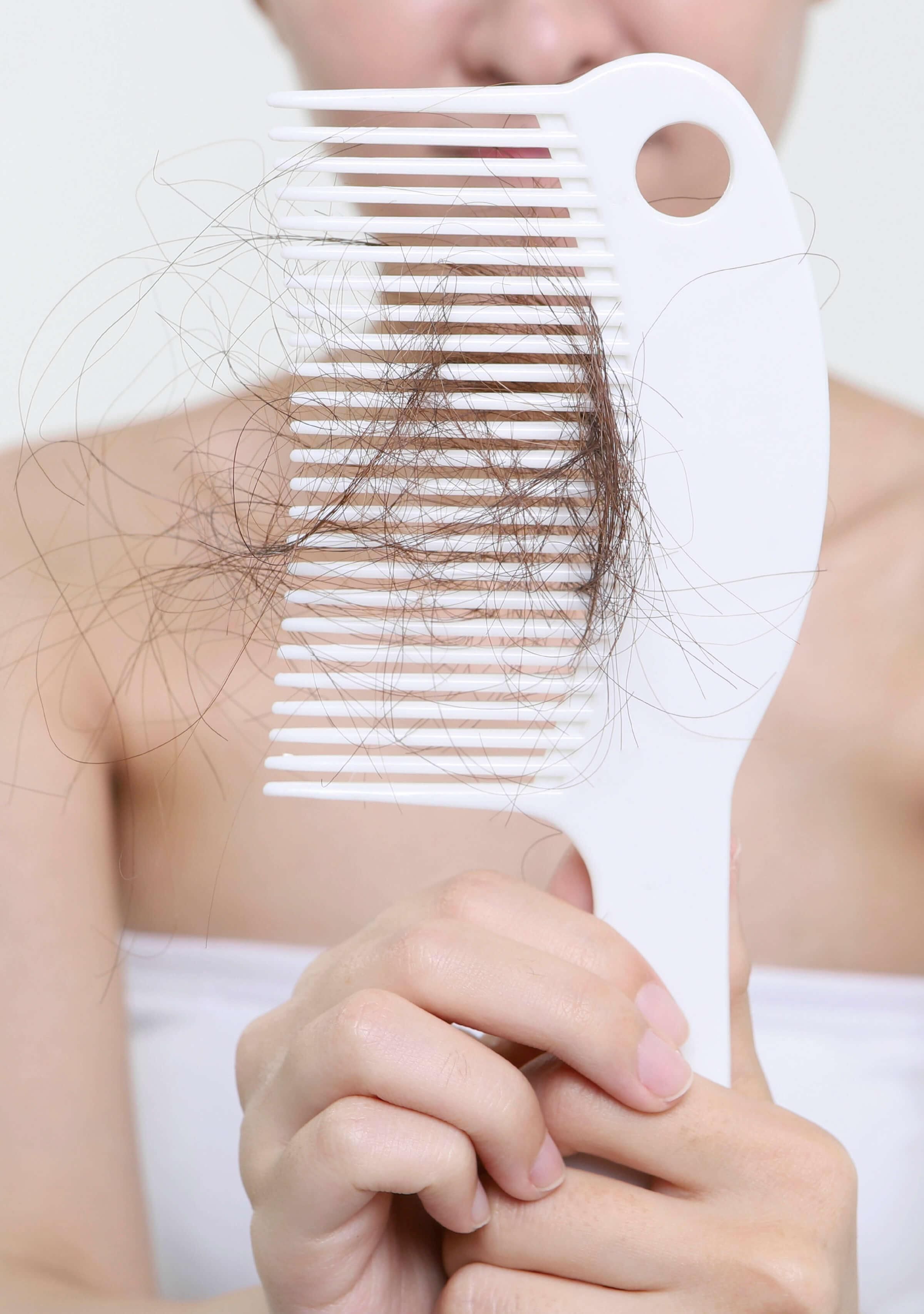 woman holding hair comb with hair strands in it