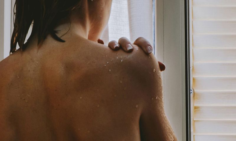 woman's bare back standing near window