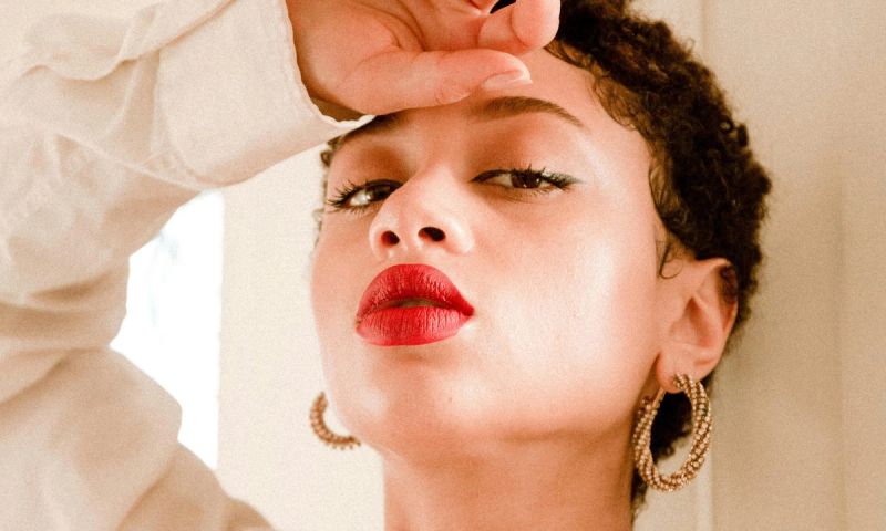 Woman looking at camera wearing red lipstick and gold hoop earrings