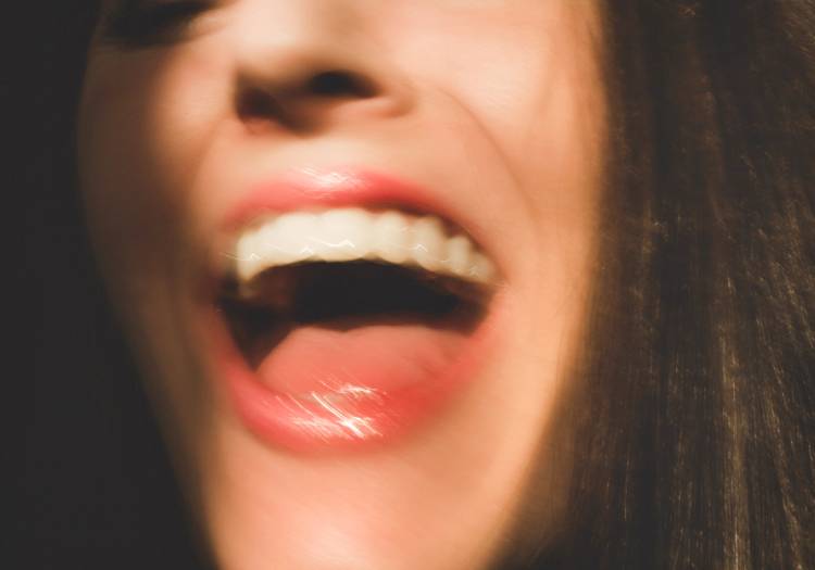 Close-up of a woman's open mouth and teeth against a dark background, illustrating dry mouth and oral health concerns during menopause
