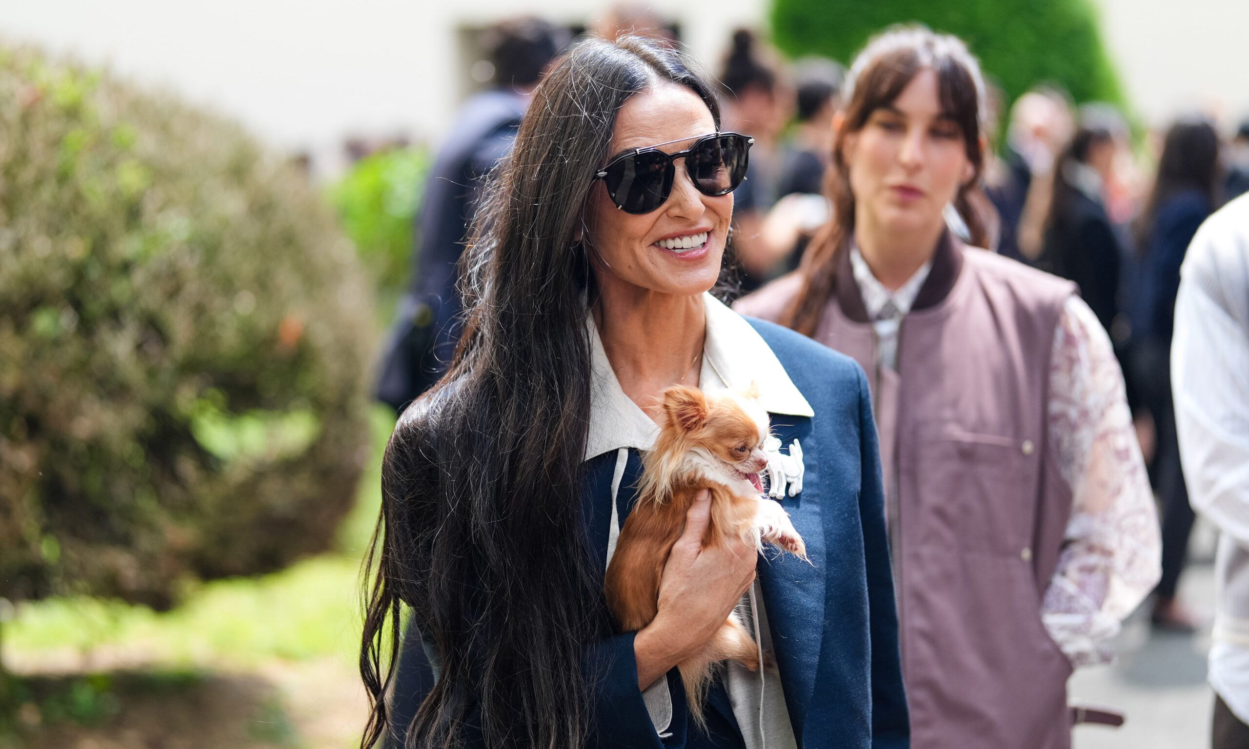 Demi Moore in sunglasses outdoors with long hair and holding a small dog