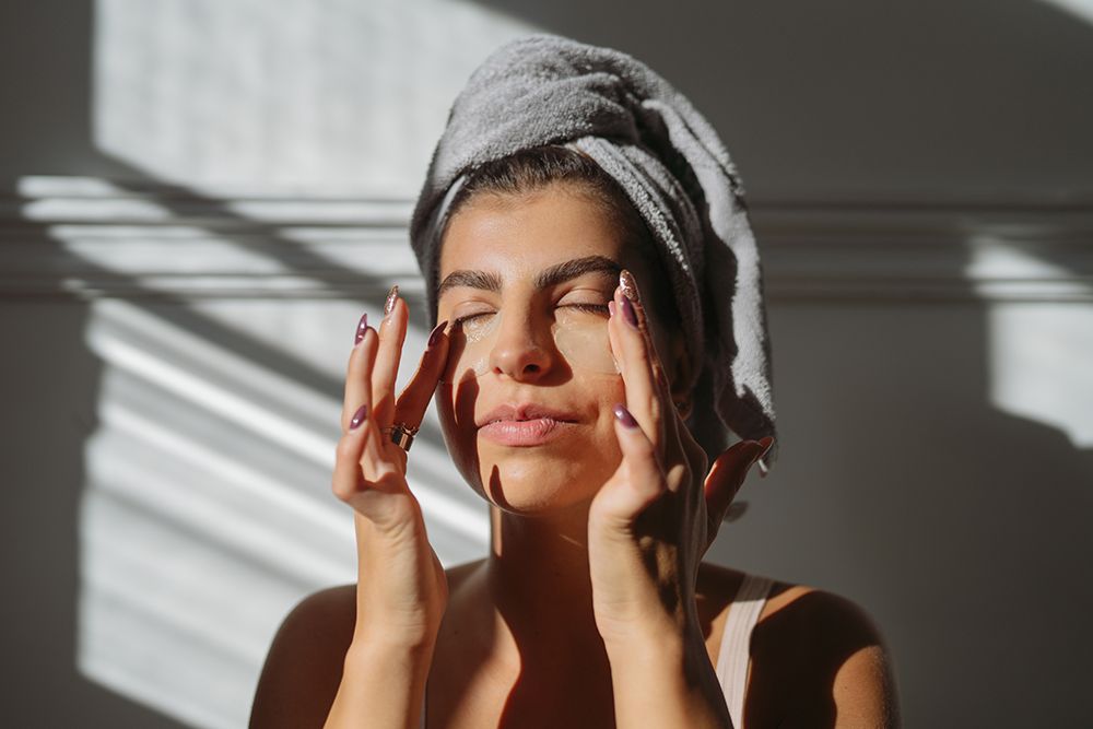 Photo of a young woman applying under-eye patches