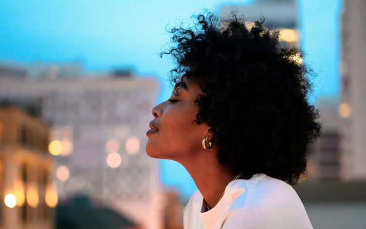 Black woman with short curly hair outdoors in a city