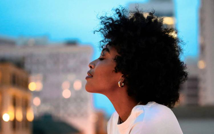 Black woman with short curly hair outdoors in a city