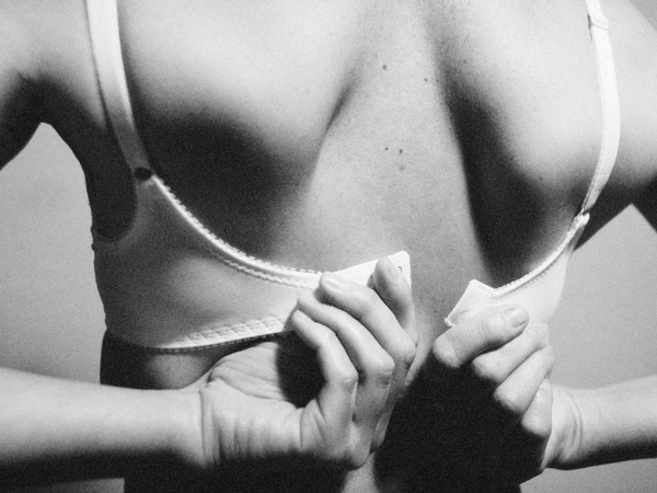 black and white back view of woman unhooking bra