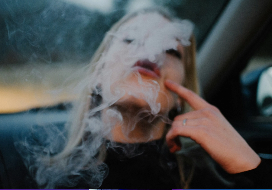 Person smoking and exhaling smoke, illustrating the effects of smoking on skin health and premature aging.