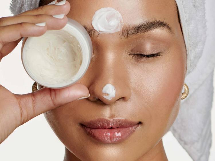 woman with eyes closed holding face cream