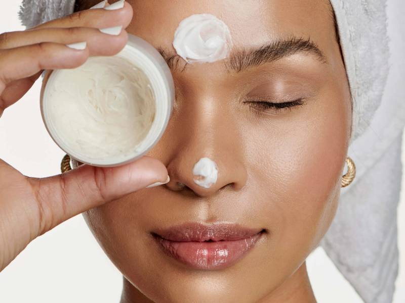 woman with eyes closed holding face cream