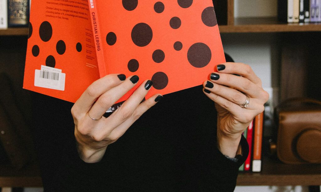 woman with black nails reading textbook