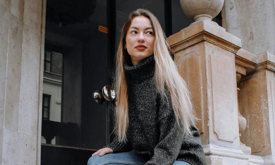 French woman with long blonde hair sitting outside in a city