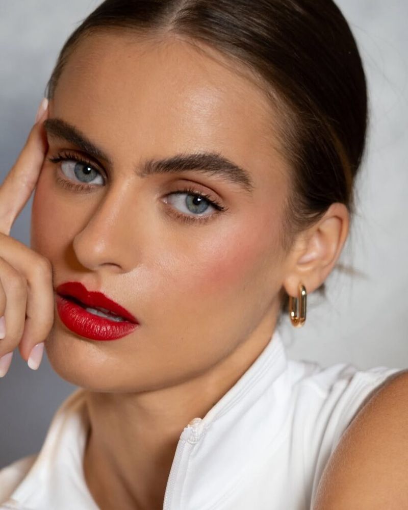 Model with dark eyebrows and bold red lipstick