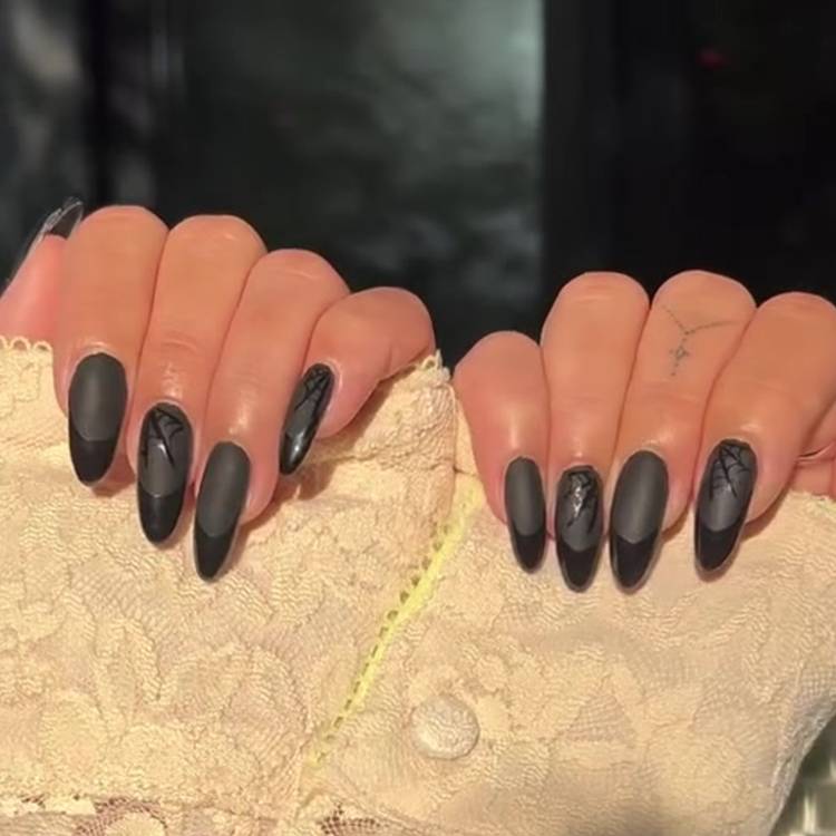 Almond-shaped matte black nails with glossy black tips. Several accent nails have glossy black spiderweb designs.