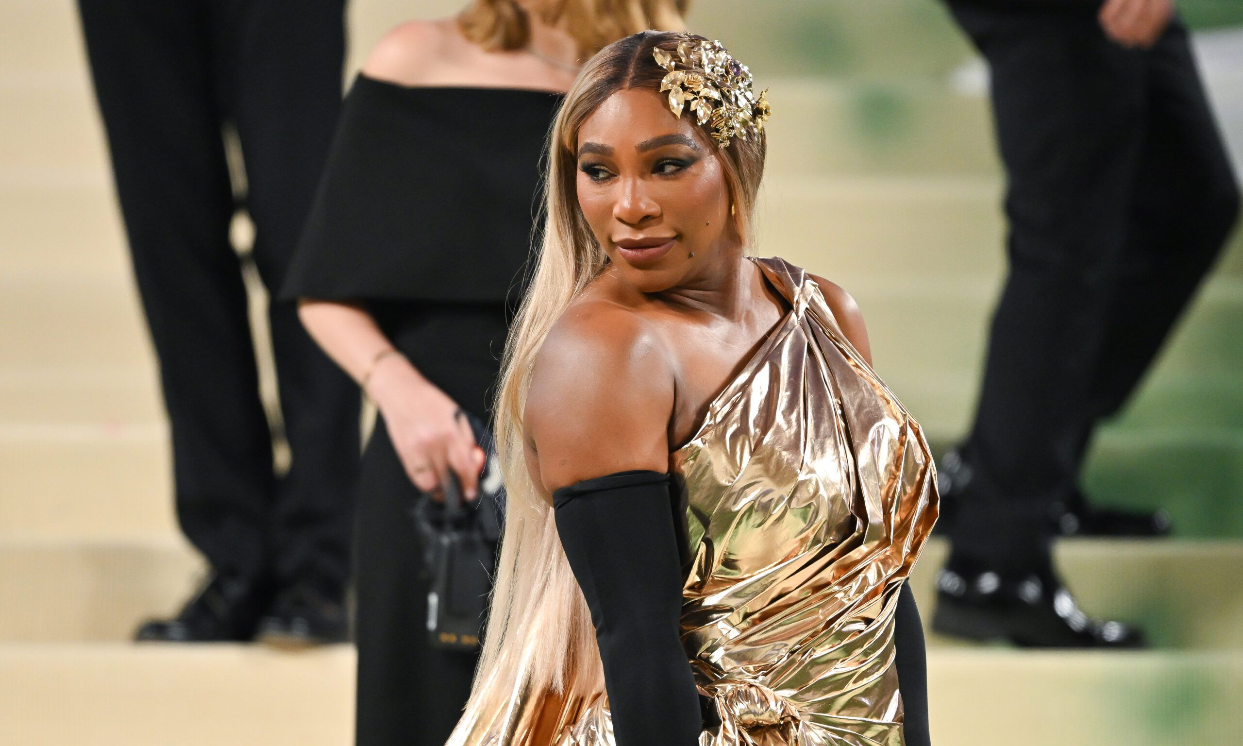 Serena Williams attends the 2024 Met Gala in gold dress and black gloves