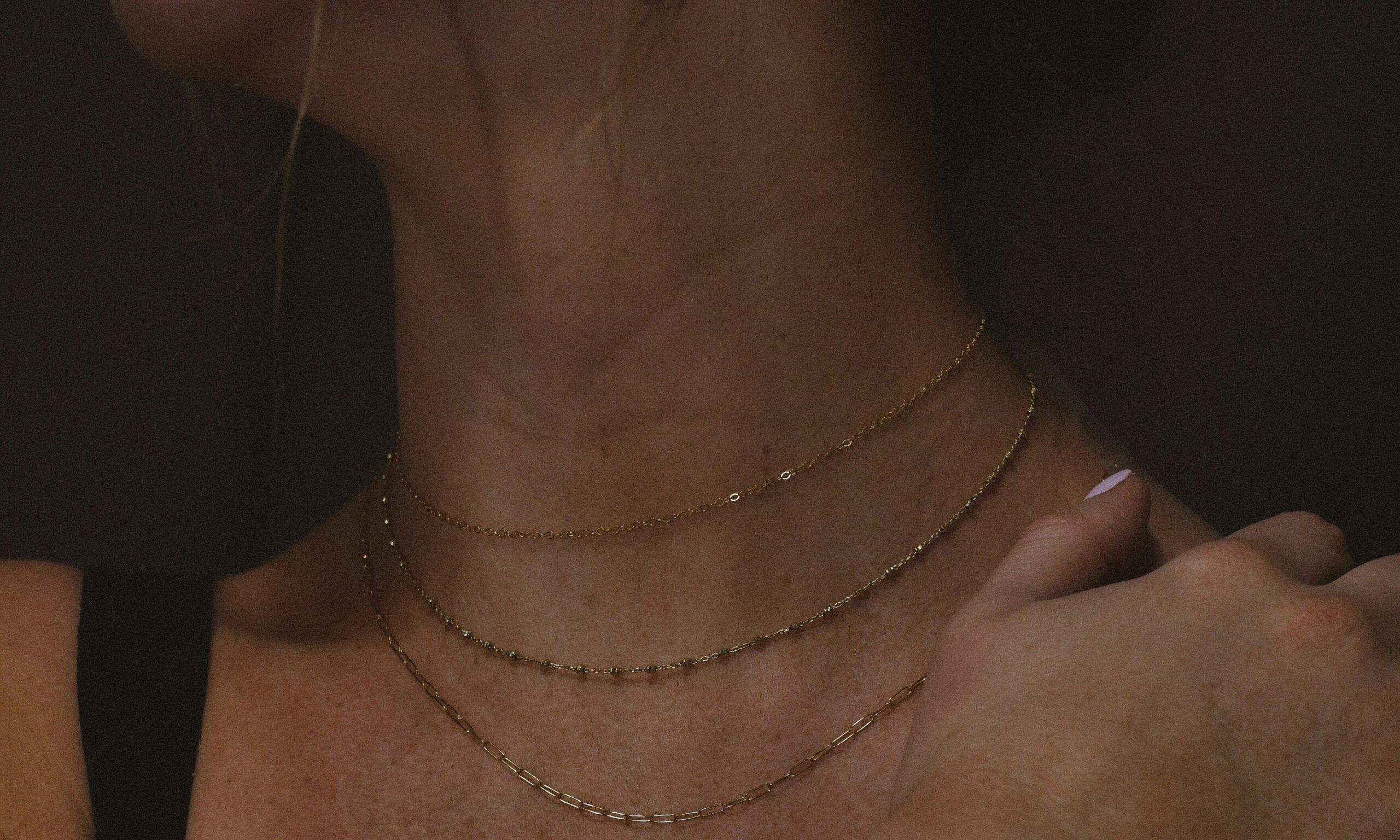 close up of woman's neck wearing dainty gold chains