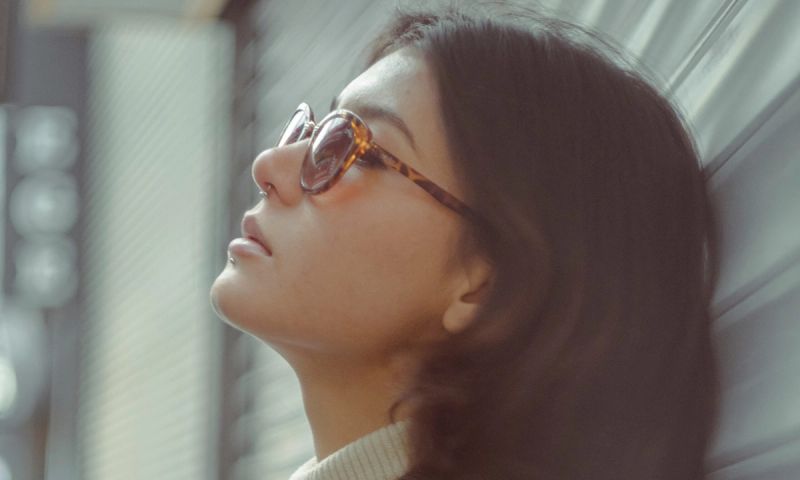 a woman wearing glasses leaning against a wall
