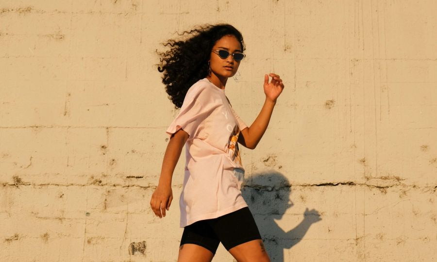 Woman with curly hair walking outdoors with sunglasses