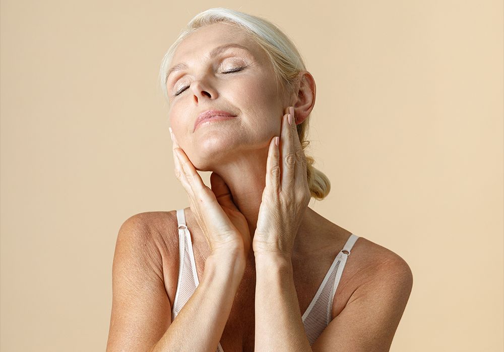 woman in front of beige background touching face