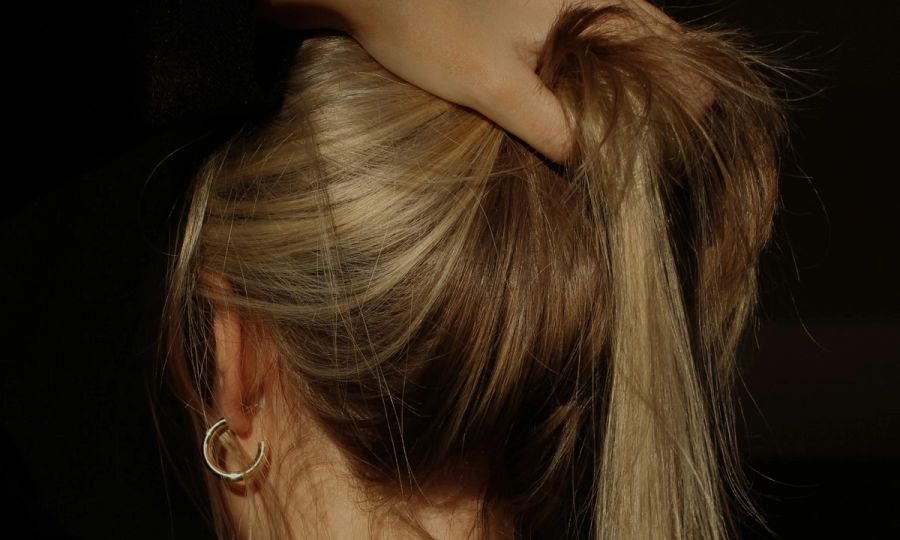 back view of woman holding blonde hair up in ponytail