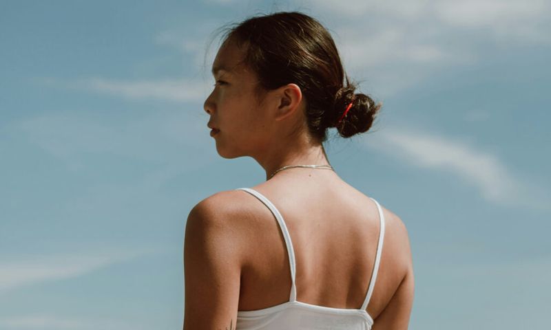 back view of Asian woman standing outdoors and looking away