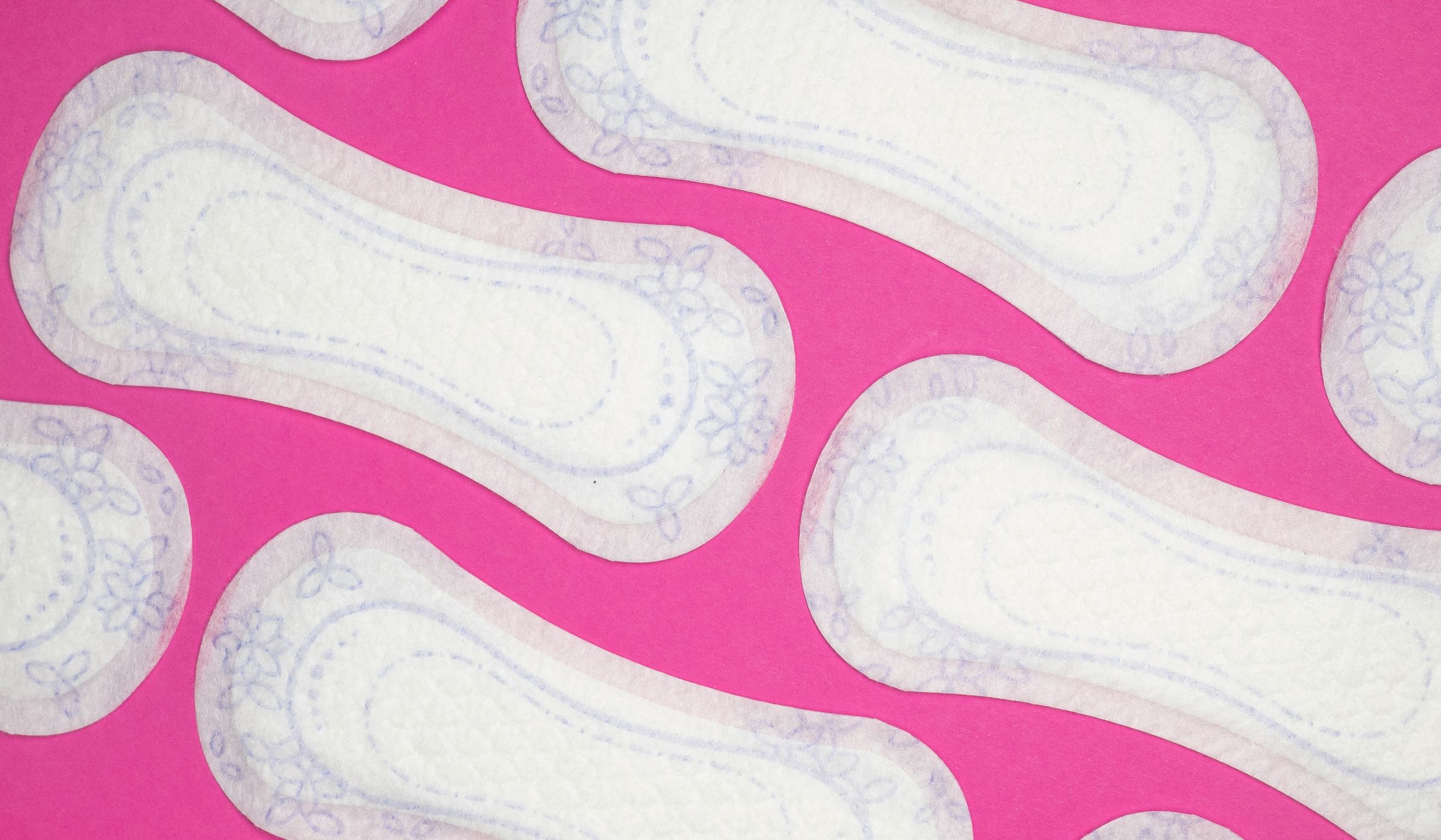 White floral-print menstrual pads scattered on a pink background.