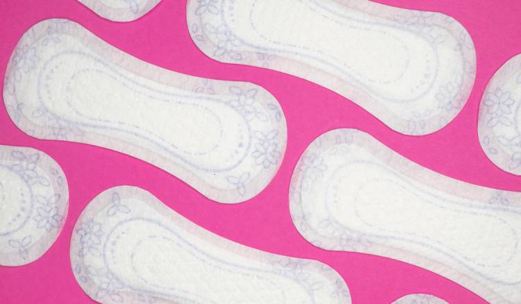 White floral-print menstrual pads scattered on a pink background.