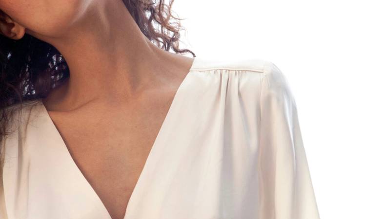 close view of woman's chest wearing a v-neck white blouse
