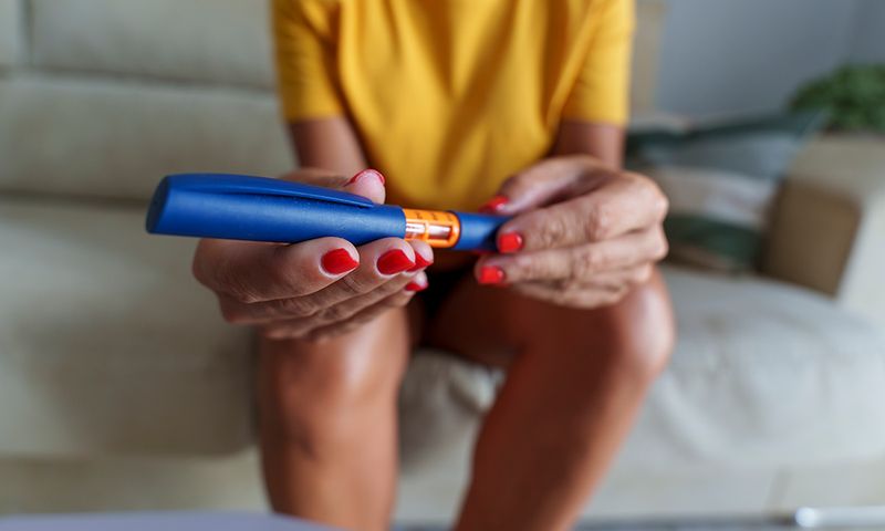Unrecognizable mid aged woman using insulin pen to control blood sugar levels