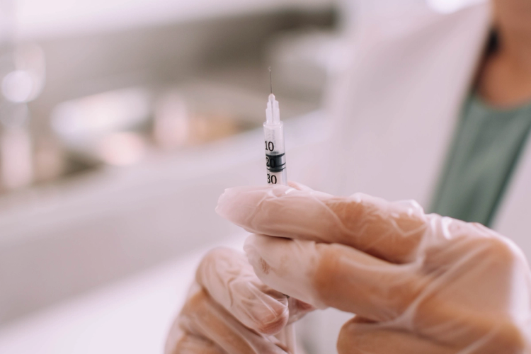 Gloved hands holding a syringe
