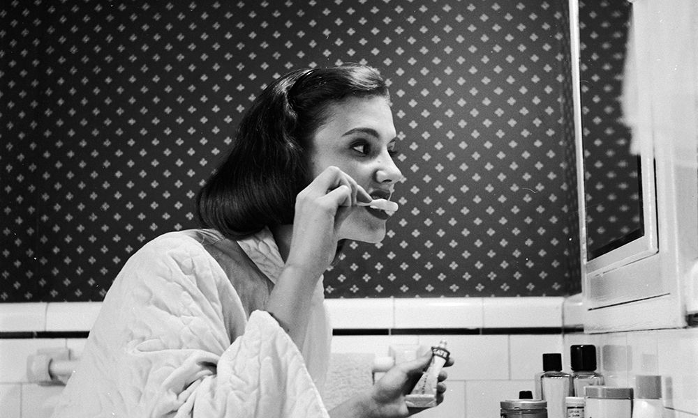 circa 1955: A young woman brushing her teeth in her bathroom. (Photo by Three Lions/Getty Images)