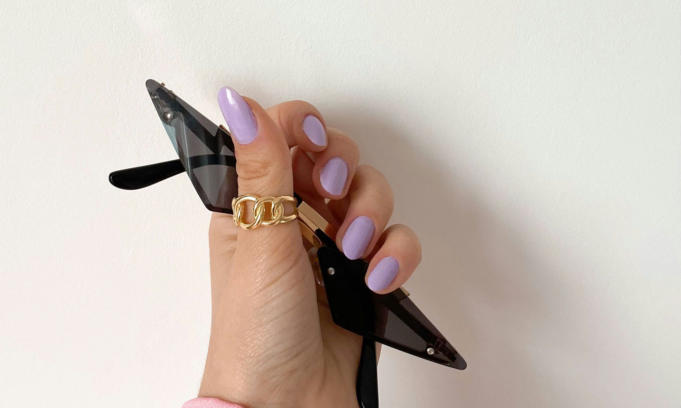 hand with purple nail polish holding sunglasses