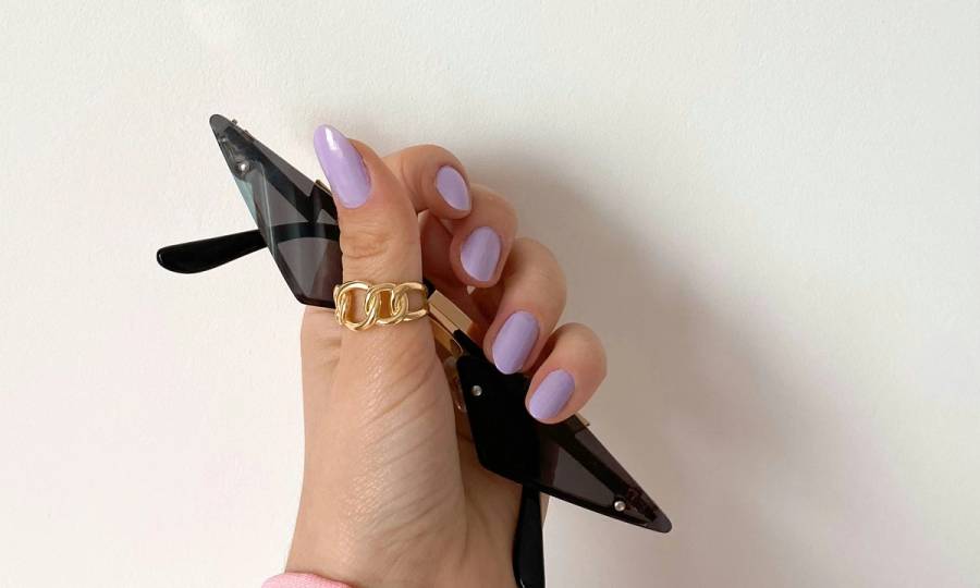 hand with purple nail polish holding sunglasses