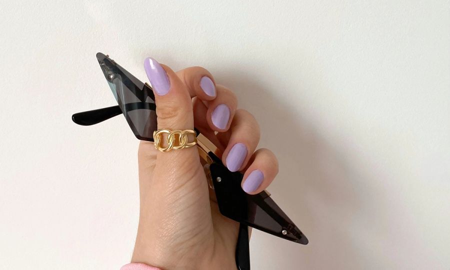 hand with purple nail polish holding sunglasses