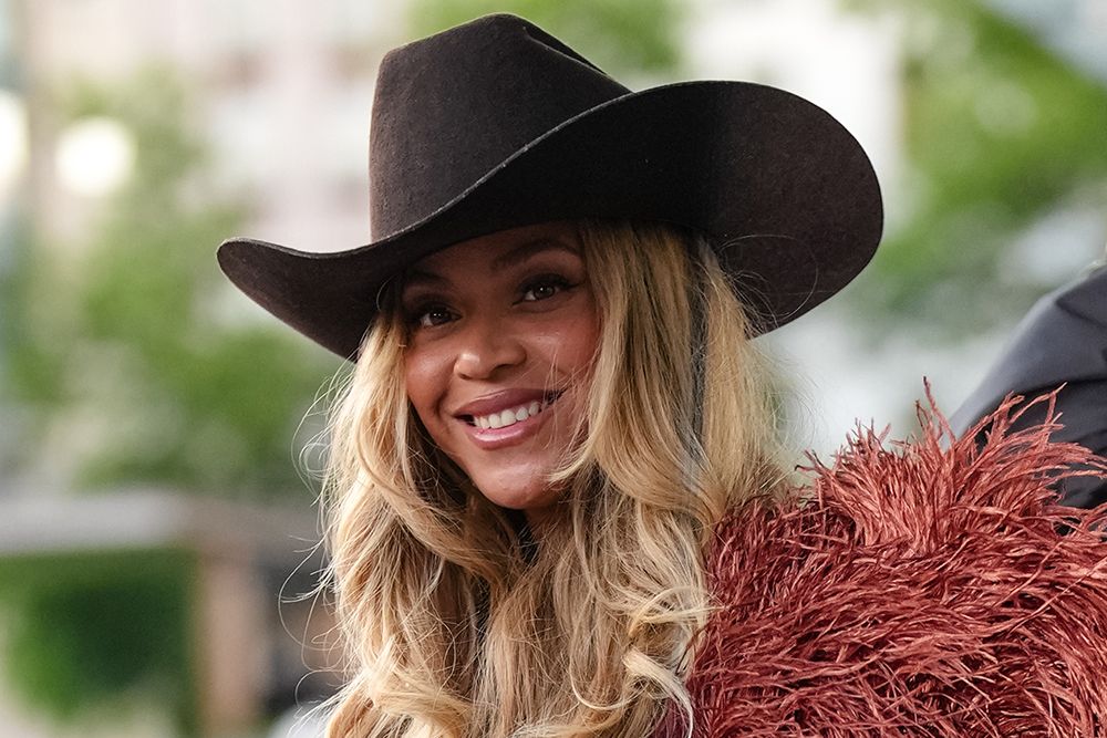 PARIS, FRANCE - JUNE 24: Beyoncé Knowles / Beyonce wears a cowboy hat, a burgundy faux fur fluff coat on one shoulder, a blue denim shirt, during the Louis Vuitton Menswear Spring/Summer 2026 show as part of Paris Fashion Week on June 24, 2025 in Paris, France. (Photo by Edward Berthelot/Getty Images)