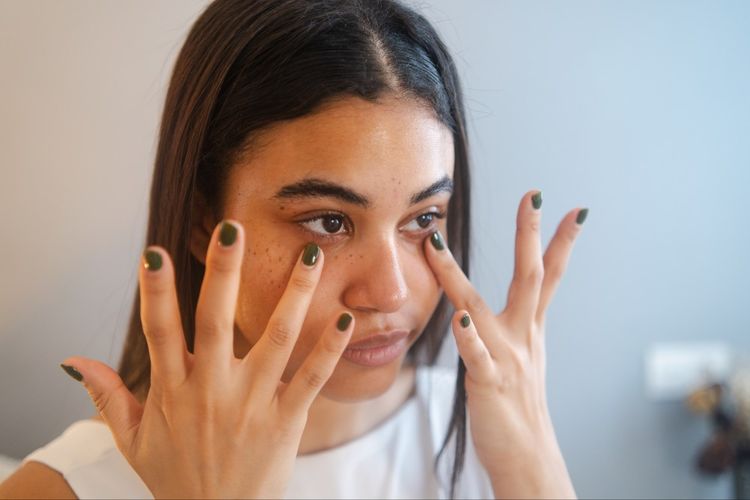 woman applying eye product to undereyes