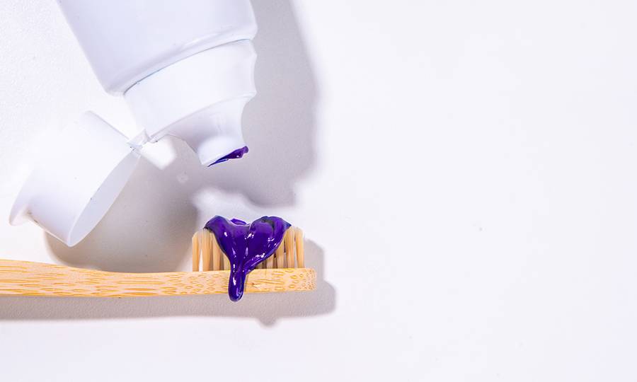 Trendy whitening purple Toothpaste, korean asian toothpaste with toothbrush and white unrecognizable tooth cleaning paste tube copy space