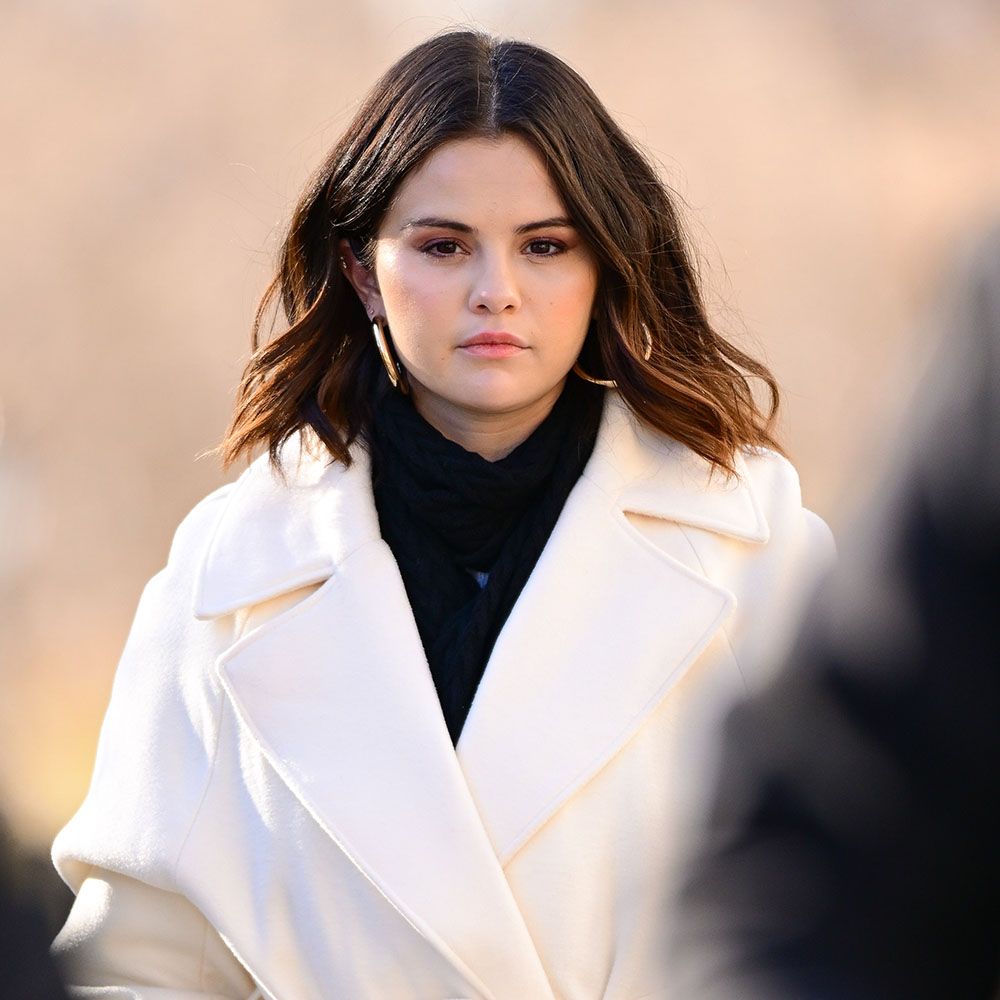 Selena Gomez walking in black turtleneck and white coat