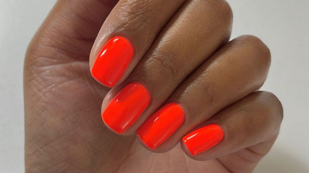 a close-up of short nails with bright red polish