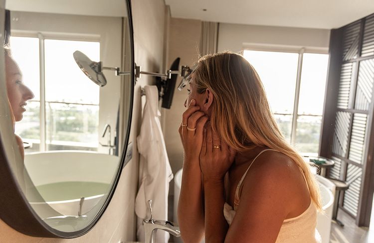 Woman looking at blemishes in mirror