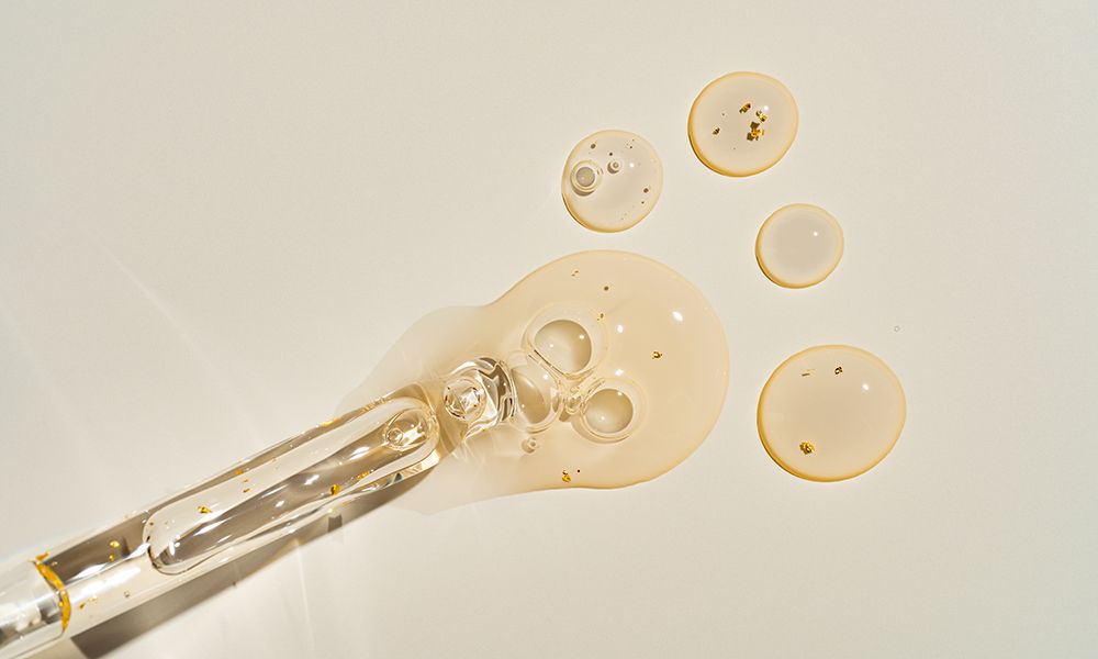 Top-view mockup of a glass dropper bottle with cosmetic pipette on trendy beige backdrop. Harsh sunlight accentuates the organic beauty product's premium packaging for clean cosmetics branding.