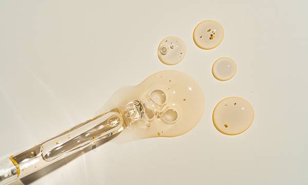 Top-view mockup of a glass dropper bottle with cosmetic pipette on trendy beige backdrop. Harsh sunlight accentuates the organic beauty product's premium packaging for clean cosmetics branding.