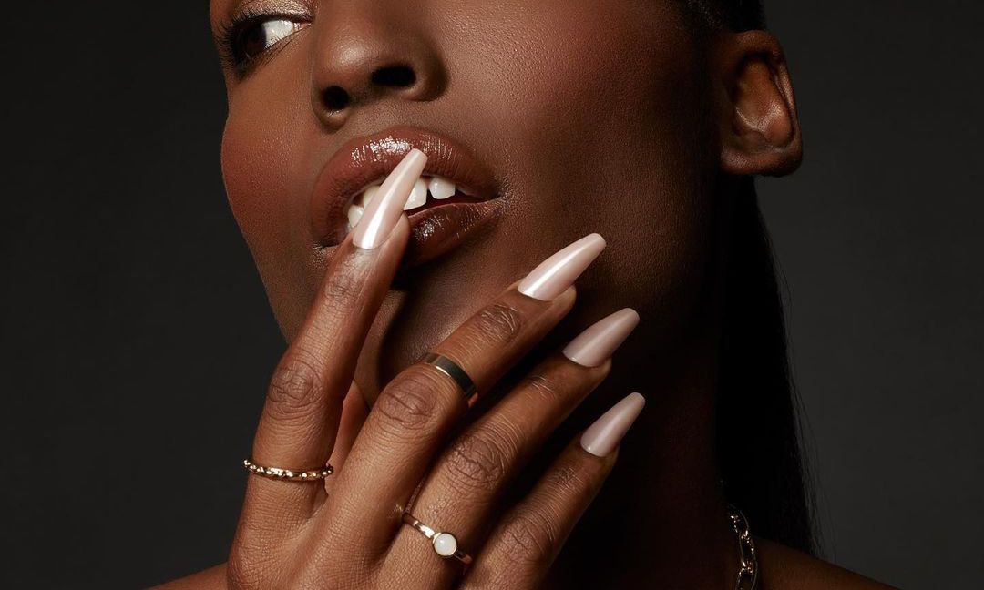 close view of woman's manicured hand on her face