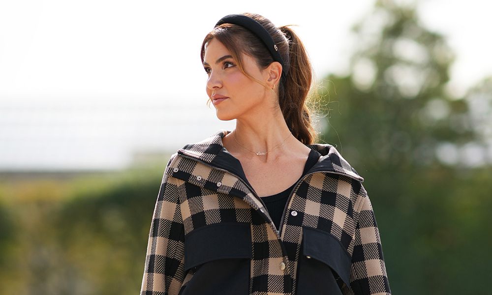 Woman wearing a headband and a beige and black checked jacket