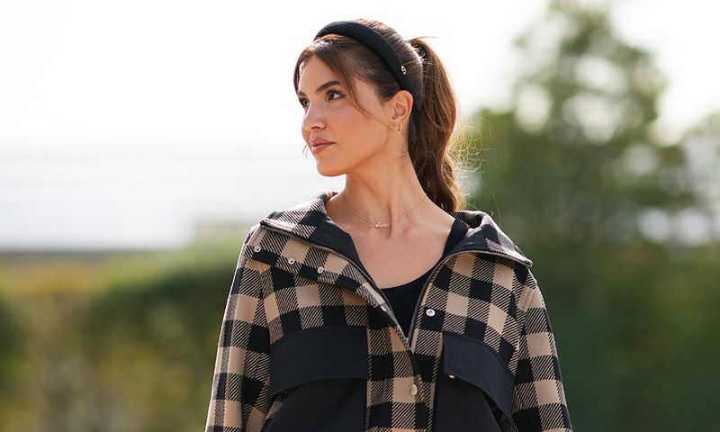 Woman wearing a headband and a beige and black checked jacket